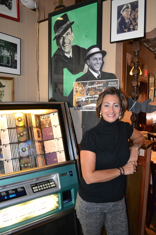 Grace Scianalepore shows off the jukebox at Leo’s Grandevous. Guess whose songs are in heavy rotation? Photo by Ken Schlager