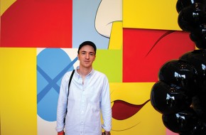 Brian Donnelly (alias KAWS) stands before his 2010 mural, “The Wall.”
