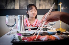 Young girl eyes sushi at a restaurant