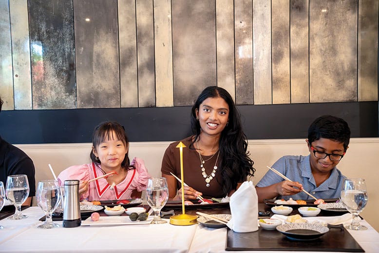 Two children and a teenager eating sushi