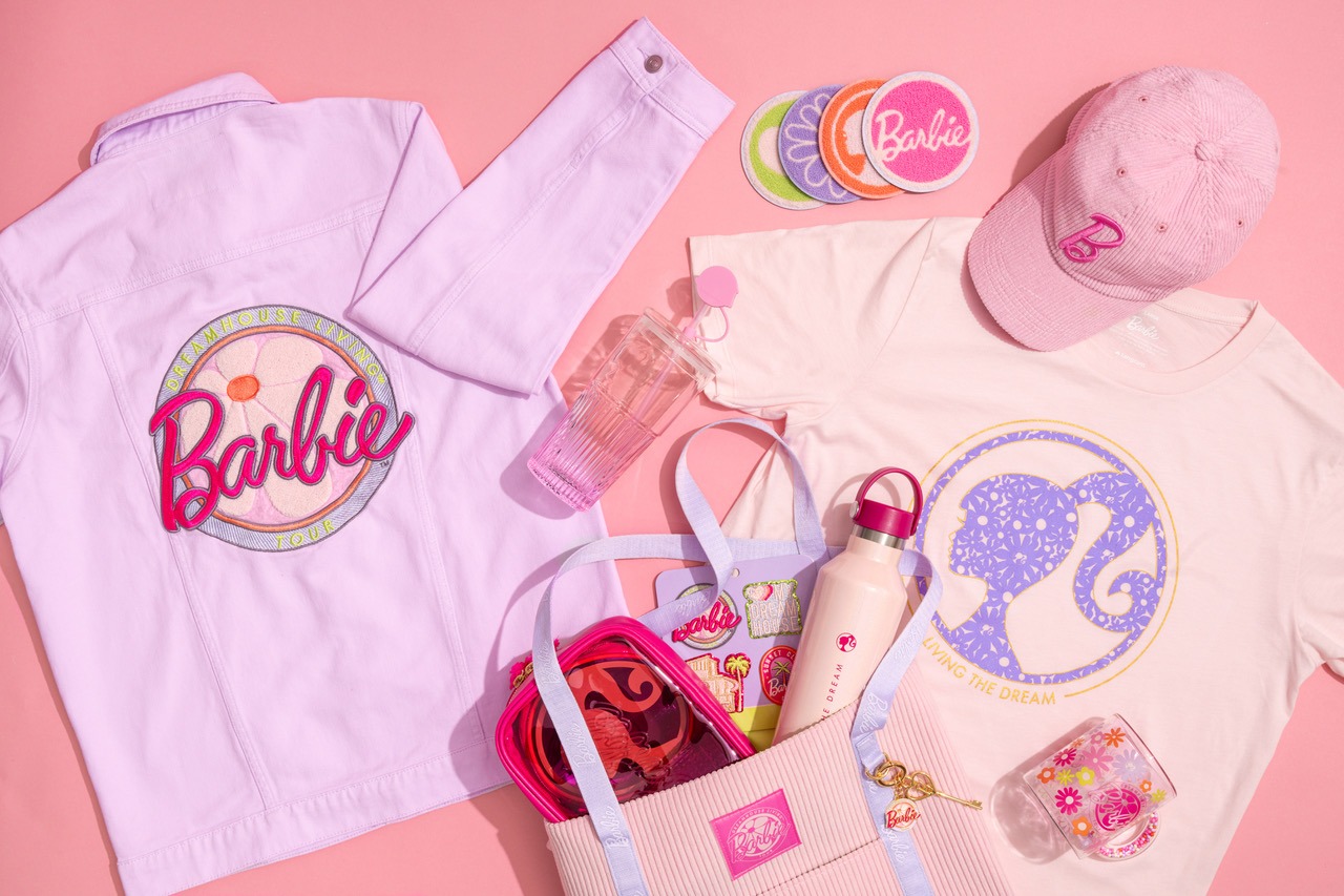 Barbie-themed merchandise, including a denim jacket, T-shirt, baseball cap, coasters, drinkware, and a tote bag filled with more Barbie-themed items