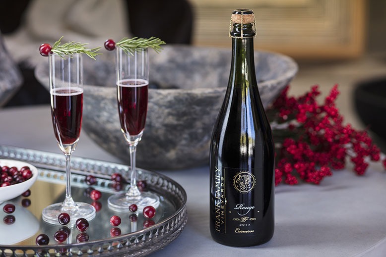 Two glasses of sparkling red wine on a table decorated for the holidays