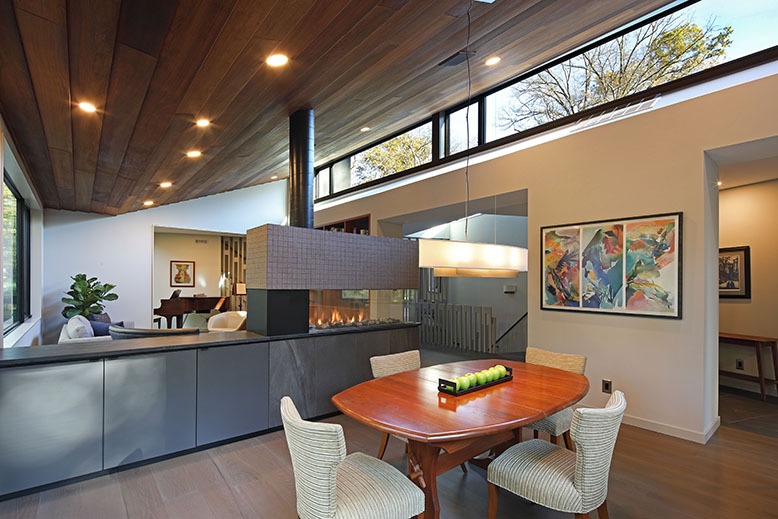 A multi-sided fireplace acts as a visual divider in an open space in Haddonfield's Hadrohouse
