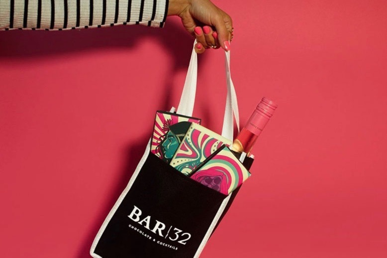 Woman holds tote from Bar 32 in Atlantic City. The bag contains three house-made chocolate bars and a bottle of wine.