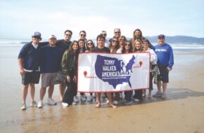 Tommy Pasquale, who walked across the U.S. to raise money and awareness for unhoused veterans, stands with a group of supporters on a beach