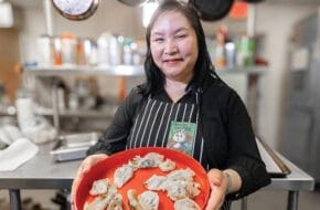 Nancy Loo of Dumpling Diplomacy holds a platter of dumplings in a kitchen