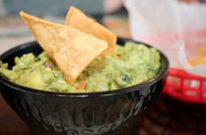 Chips perched atop a bowl of guacamole at La Cabañita