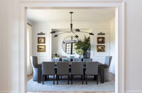 Kate Rumson's dining room features white walls, gray seating, a dark table and gold-framed artwork