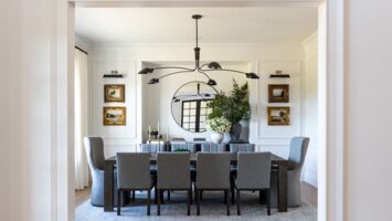 Kate Rumson's dining room features white walls, gray seating, a dark table and gold-framed artwork