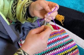 An Afghan refugee embroiders a colorful handbag