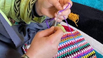 An Afghan refugee embroiders a colorful handbag