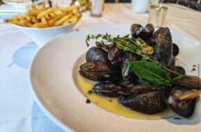 A platter of mussels in front of a bowl of fries