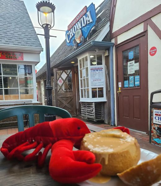 A plush lobster sits next to a sourdough bread bow filled with lobster bisque outside of LBI's Country Kettle Chowda