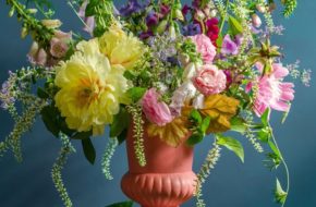 Peach-colored vase holding sprawling, colorful floral arrangement