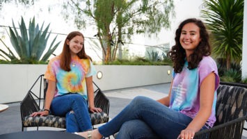 Lauren and Brooke Greenberg sit outside wearing tie-dye apparel from their brand, Tie Dye LAB