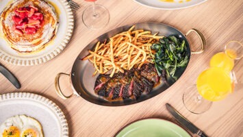 A table with plates full of pancakes, eggs and steak frites