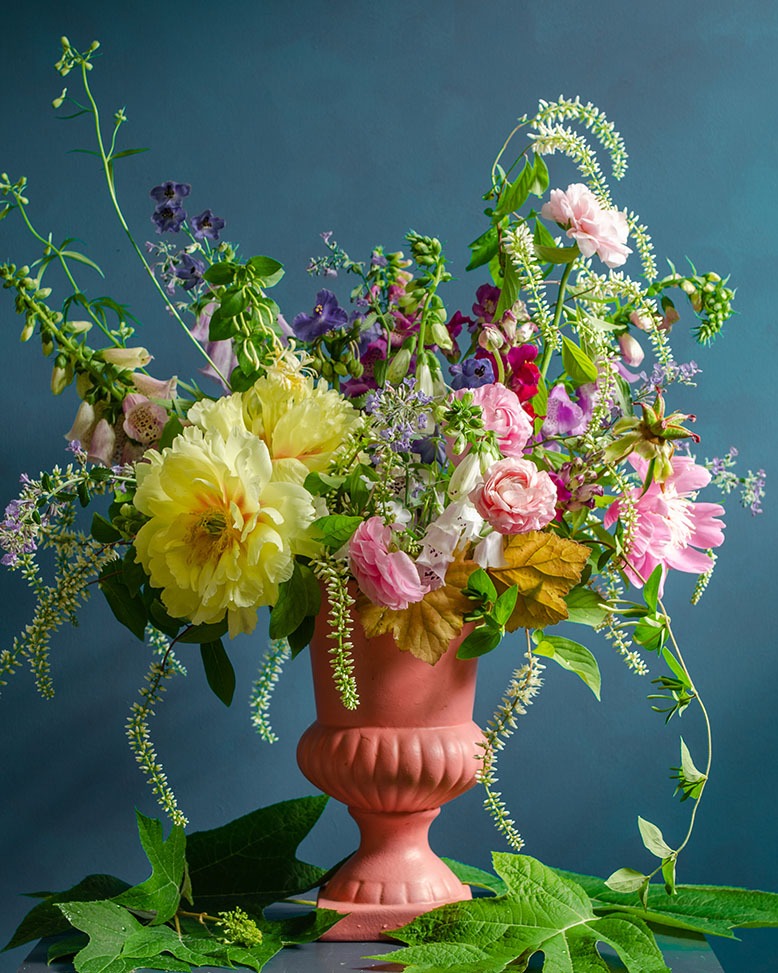 Peach-colored vase holding sprawling, colorful floral arrangement