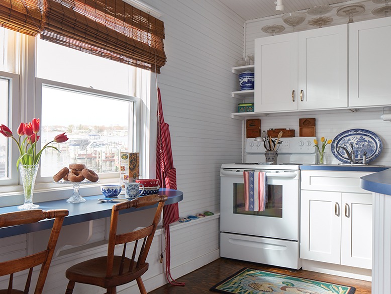 The 100-year-old houseboat's kitchen has a built-in dining table below the room's windows.