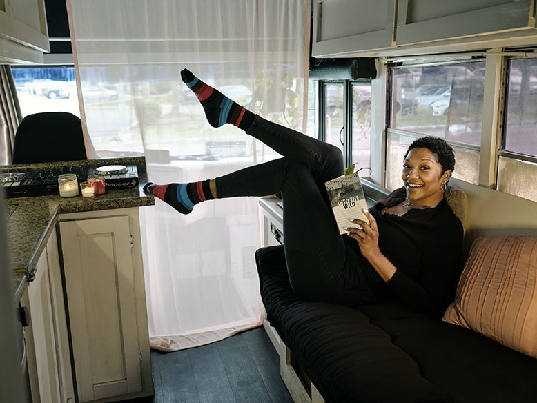 Tyler reads on the futon inside her converted school-bus home
