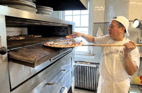 A thin-crust bar pie being pulled out of the oven at Conte’s Pizza in Princeton