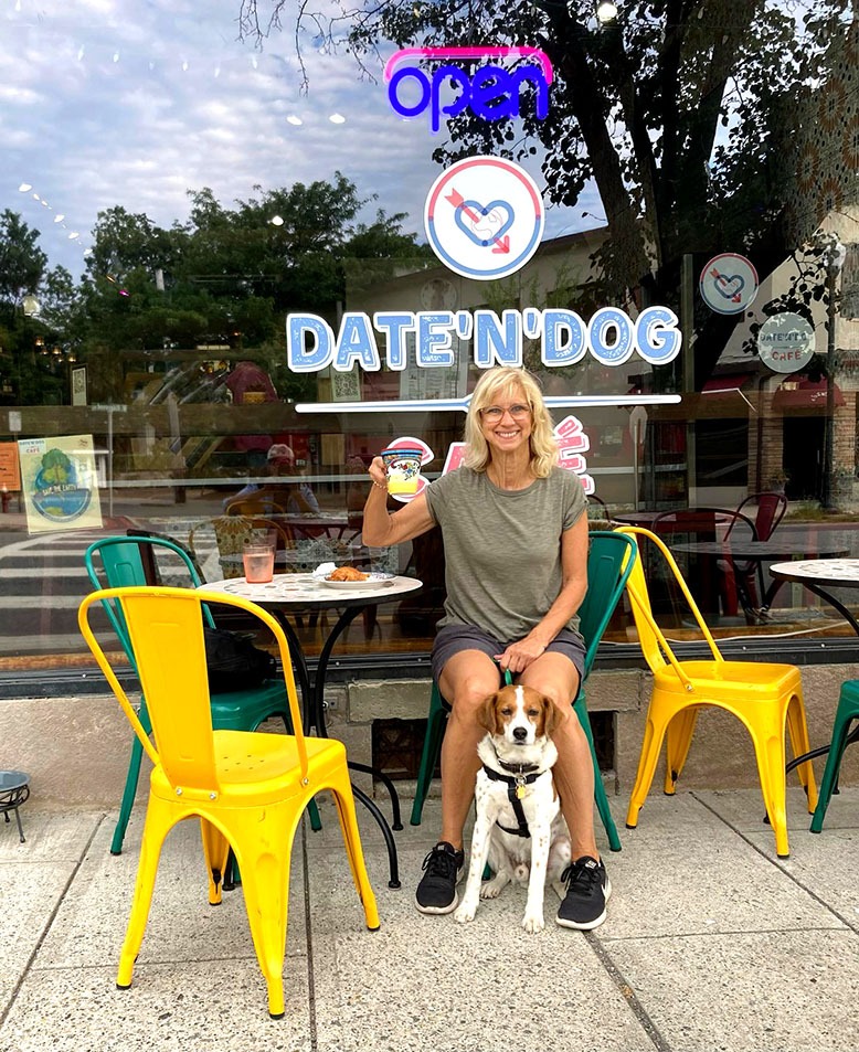 A woman enjoys at outdoor meal with her dog at Date’N’Dog in Ridgewood