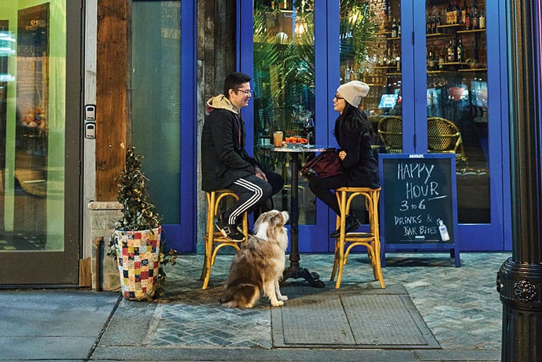 A couple and their pup sit outside a restaurant on Jersey City’s Newark Avenue