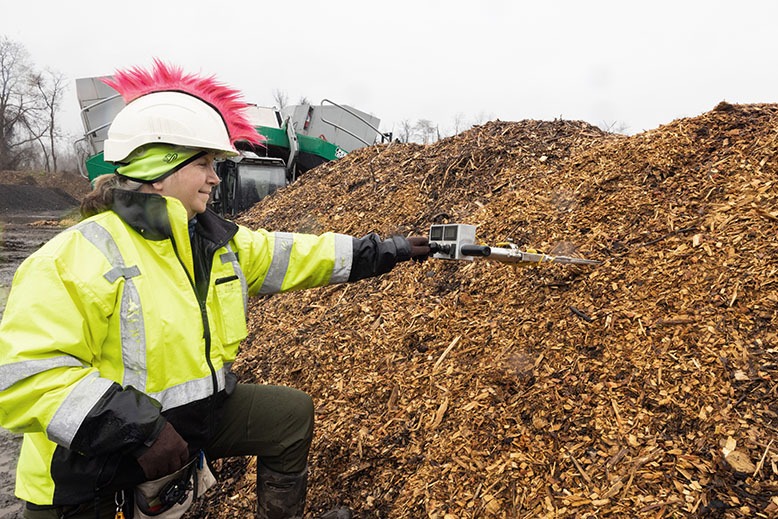 Site scientist Kristine Paff measures temperature and oxygen levels in a windrow.