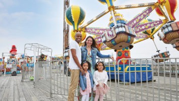 The Sarfo-Darko family amid amusement park attractions on the Point Pleasant boardwalk.