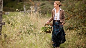 Designer Cara Brown models her custom necklace and tweed jacket in a field