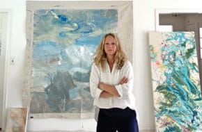 Woman artist stands in front of painting