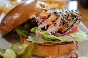 Sesame-studded, rare Ahi tuna slices piled with Asian slaw and sriracha-lime aioli are served on a fresh brioche bun at Wally's in Surf City