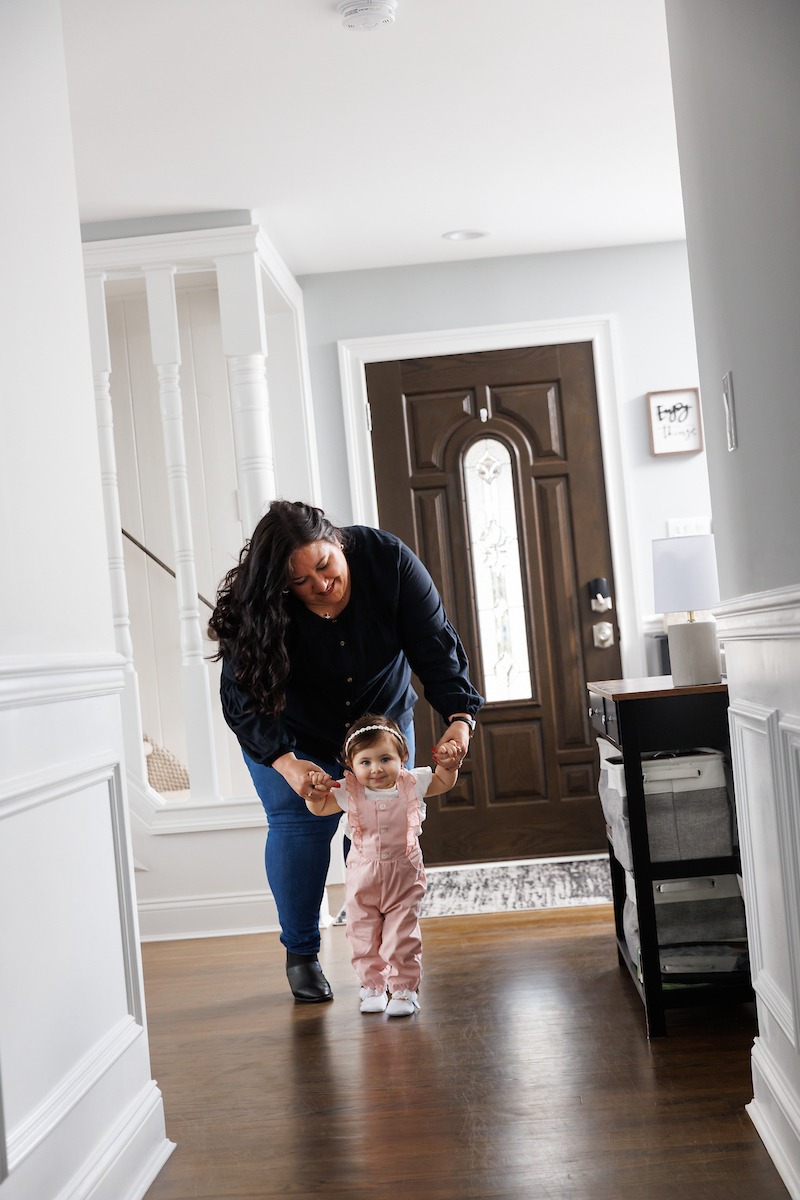 Keri Urban helps her one-year-daughter stand in the hallway of their Hasbrouck Heights home