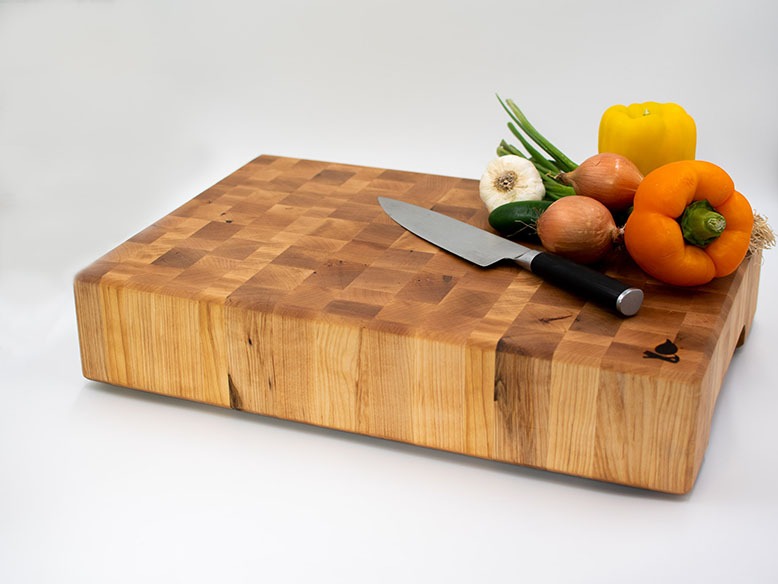 Knife and produce resting atop a thick cutting board