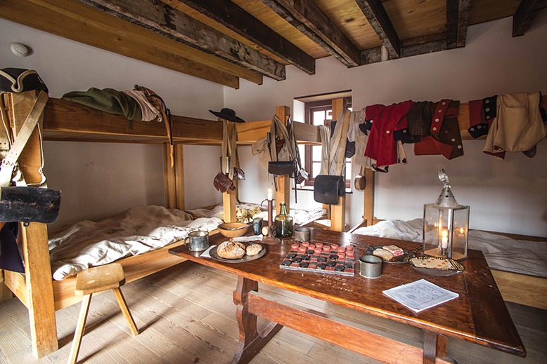 The inside of the Old Barracks Museum shows Colonial-era domestic life—beds, clothing, a table, food and games.