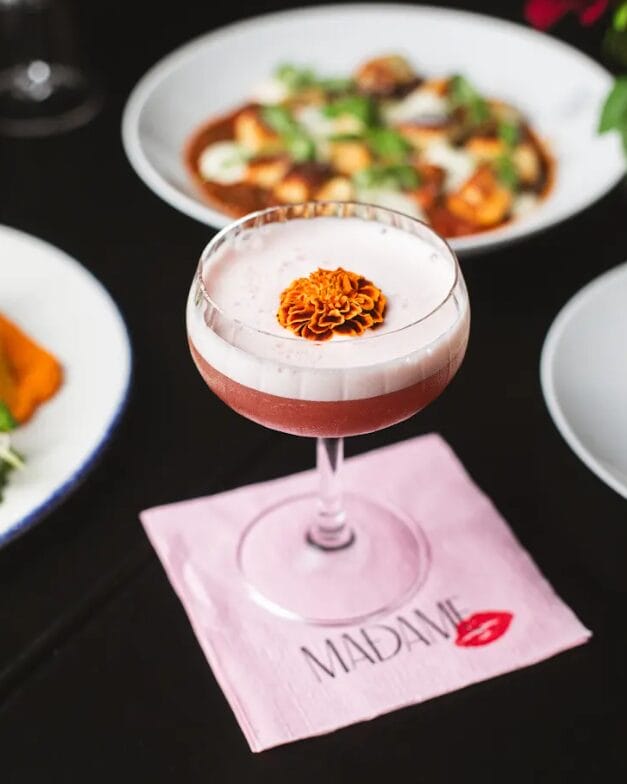 A cocktail and plate of food at Madame in Jersey City