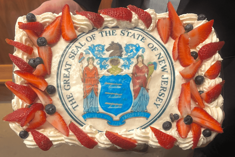 A cake decorated with strawberries, blueberries and the Great Seal of the State of New Jersey.