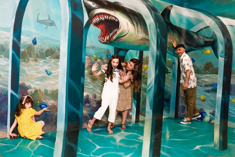 Visitors pose with a massive shark mural at the TiLT museum in East Rutherford.