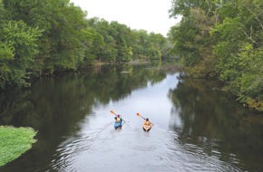 Two kayakers paddle down the Passaic River.