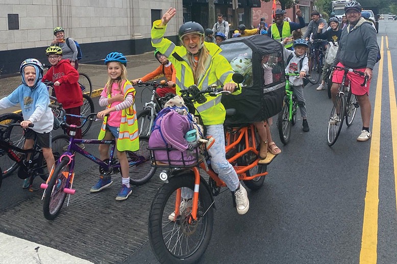 group of young bikers with adult leader in bright yellow jacket waving