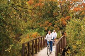 bikers on a wooden bridge in a park with fall foliage