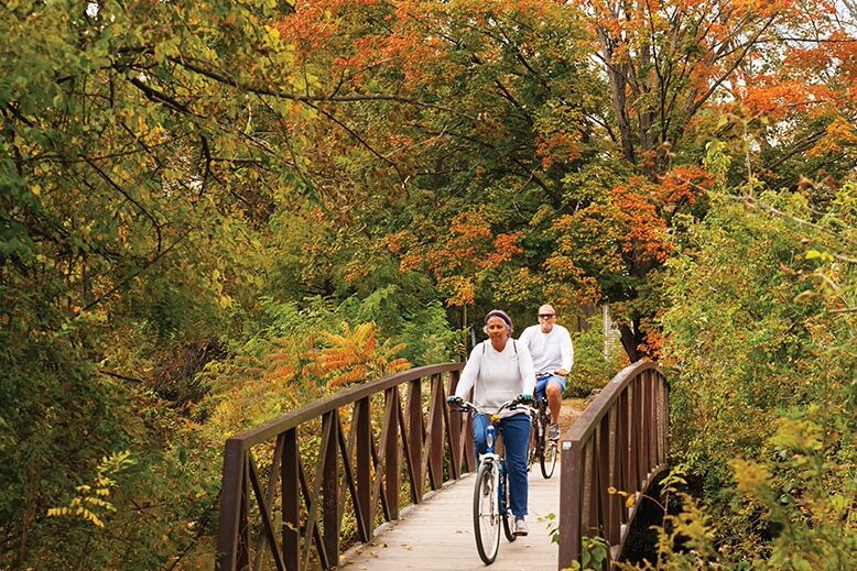 bikers on a wooden bridge in a park with fall foliage