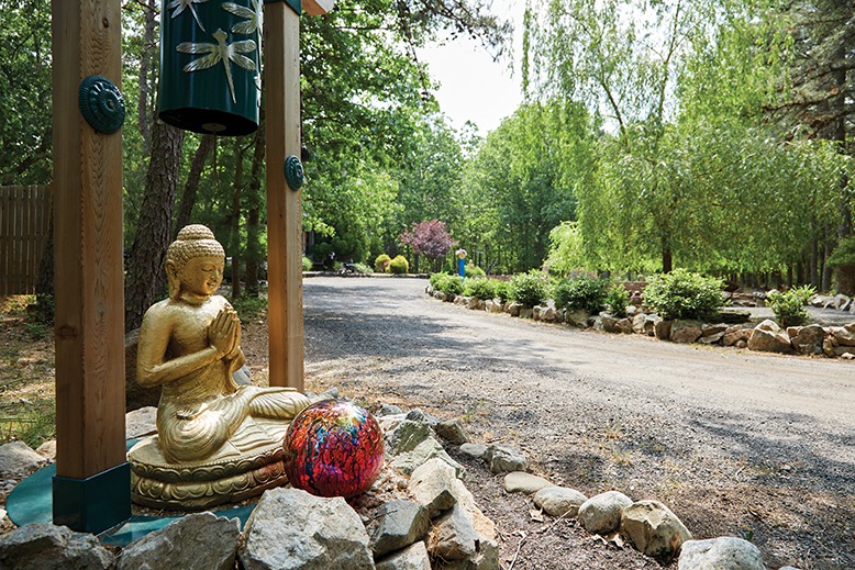 The tree-lined pathway leading to Kathleen and Philip Foley's Chatsworth home features a large golden Buddha.
