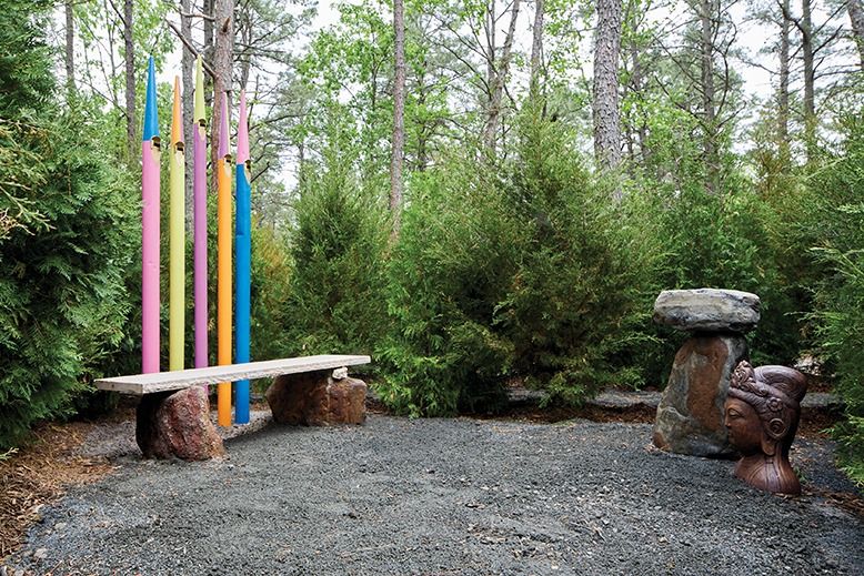 A colorful piece of Phil's artwork sits among trees, stones and sculptures.