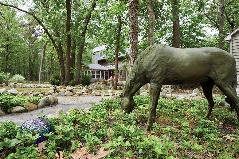 A bronze horse sculpture stands among foliage behind the Foleys' home. 