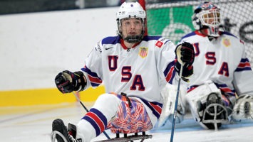 Jack Wallace, 23, on the ice. He sits on a bucket-seat sled, which has skating blades underneath.