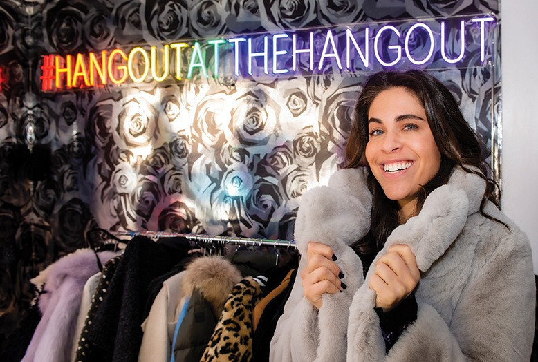 Lauren Turk tries on a fur coat at the Hangout, her Englewood consignment shop.