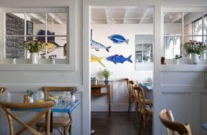 The white and neutral dining room at Louisa's Cafe in Cape May features charming pops of blue and yellow
