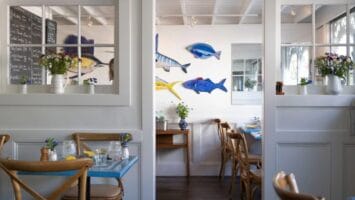 The white and neutral dining room at Louisa's Cafe in Cape May features charming pops of blue and yellow