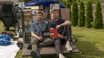 Dillon Carroll of Ridgewood and Mark Kreynovich sit in front of a car loaded with supplies for their newly formed organization, Mission to Ukraine