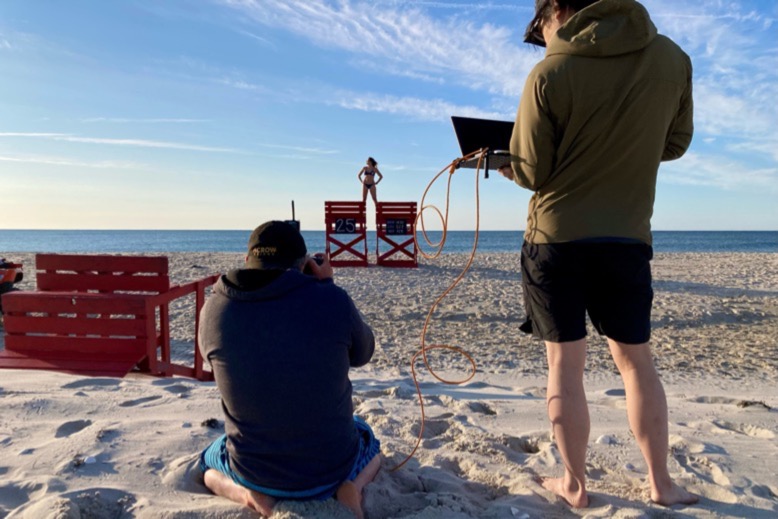 Dave Moser photographs a Jersey Shore lifeguard, who stands with each foot on two lifeguard chairs